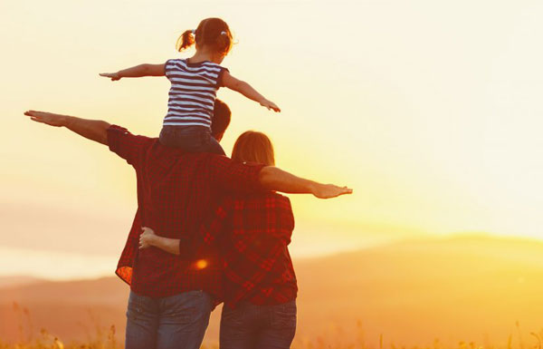 Father and Mother looking at the sunset with their infant atop father's shoulders